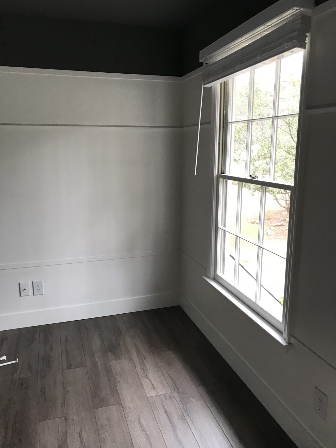 DIY small bedroom makeover with before/after photos showing how to remove wallpaper and popcorn ceilings and add new laminate flooring on a budget.